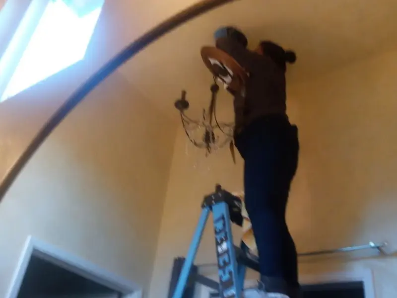 Electrician installing a chandelier in a Henryetta residence
